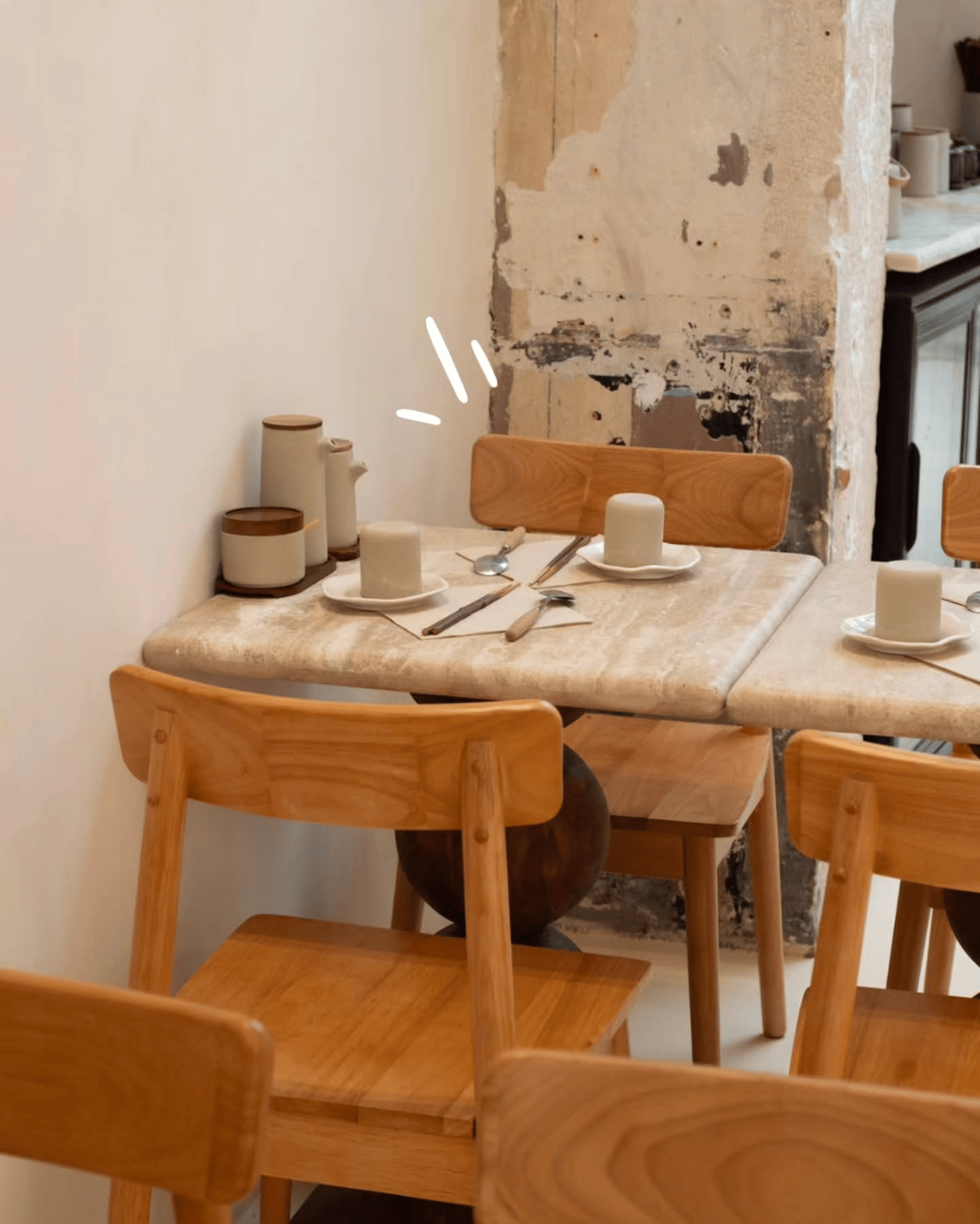 Petite table dressée avec chaises en bois et colonne de pierre