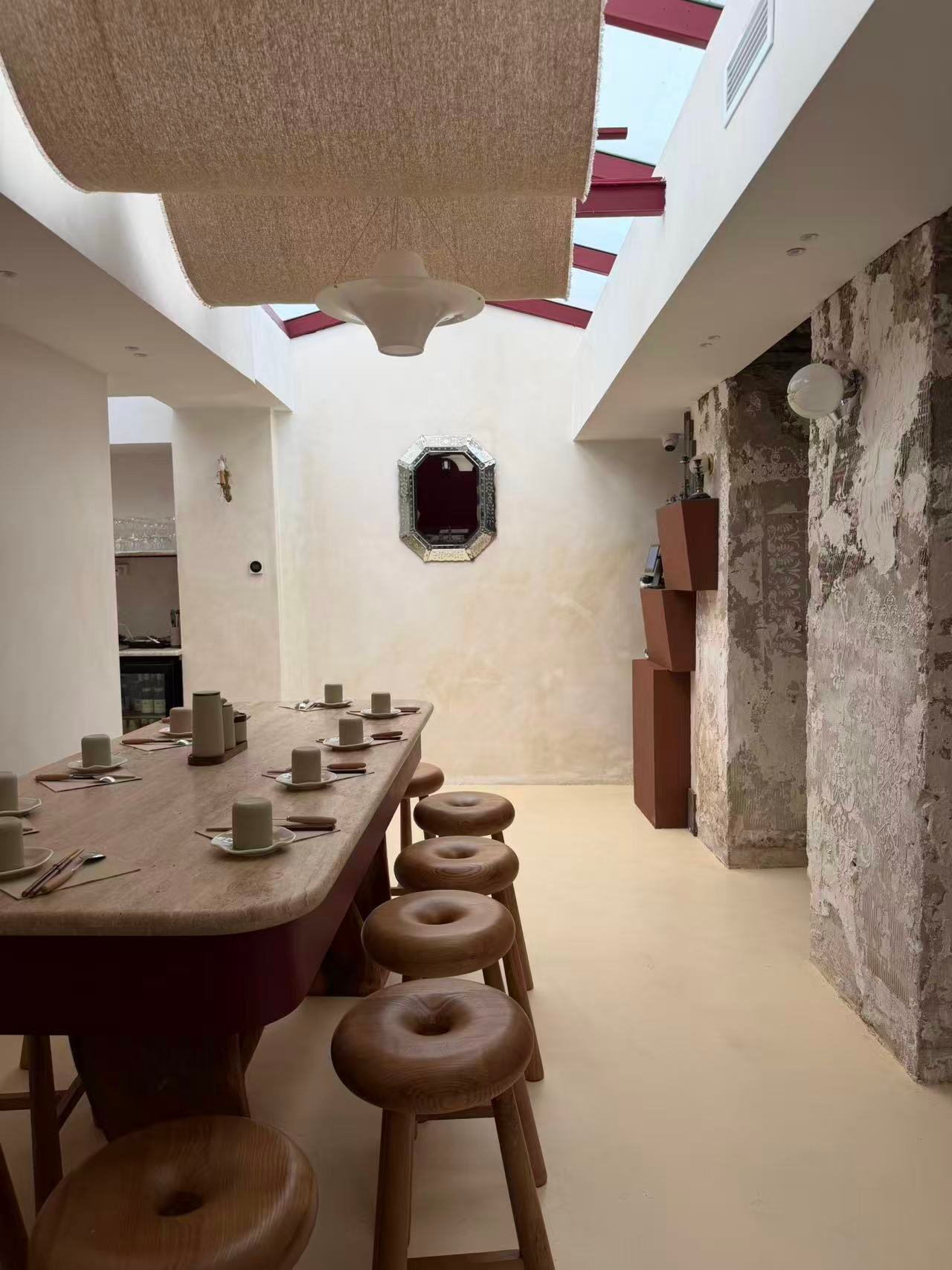 Salle vue depuis le mur de pierre, tabourets et miroir vénitien